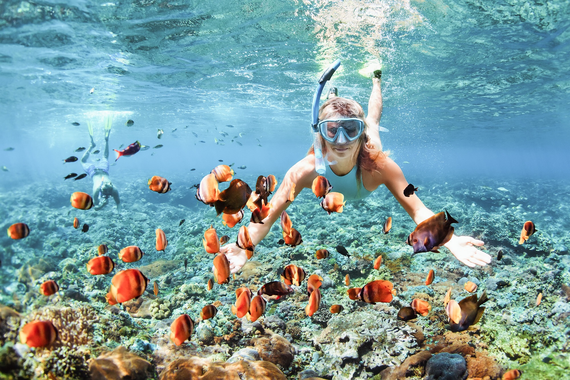 Happy couple snorkeling underwater over coral reef